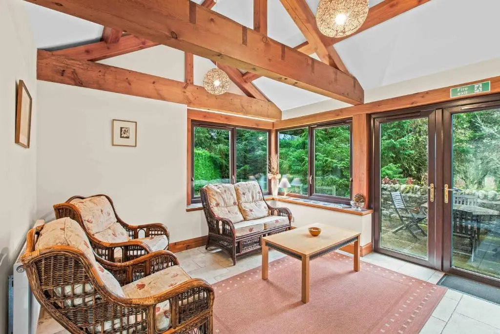 a living room with chairs and a table and windows at Freuchies Mill - A Holiday Home For All Seasons. in Blairgowrie