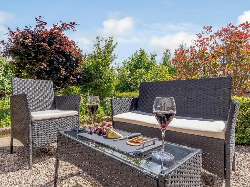 two chairs and a table with two glasses of wine at Torreagles in Mintlaw