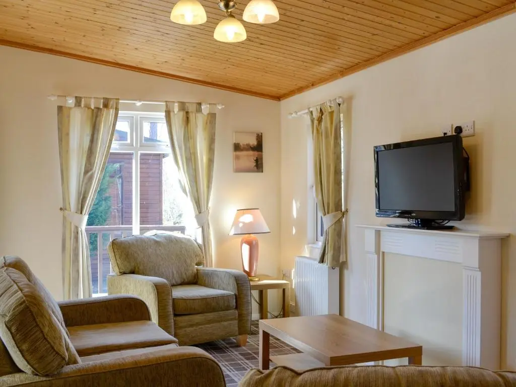 a living room with a tv and a couch and chairs at Lodge C- Uk33089 in Dinnet