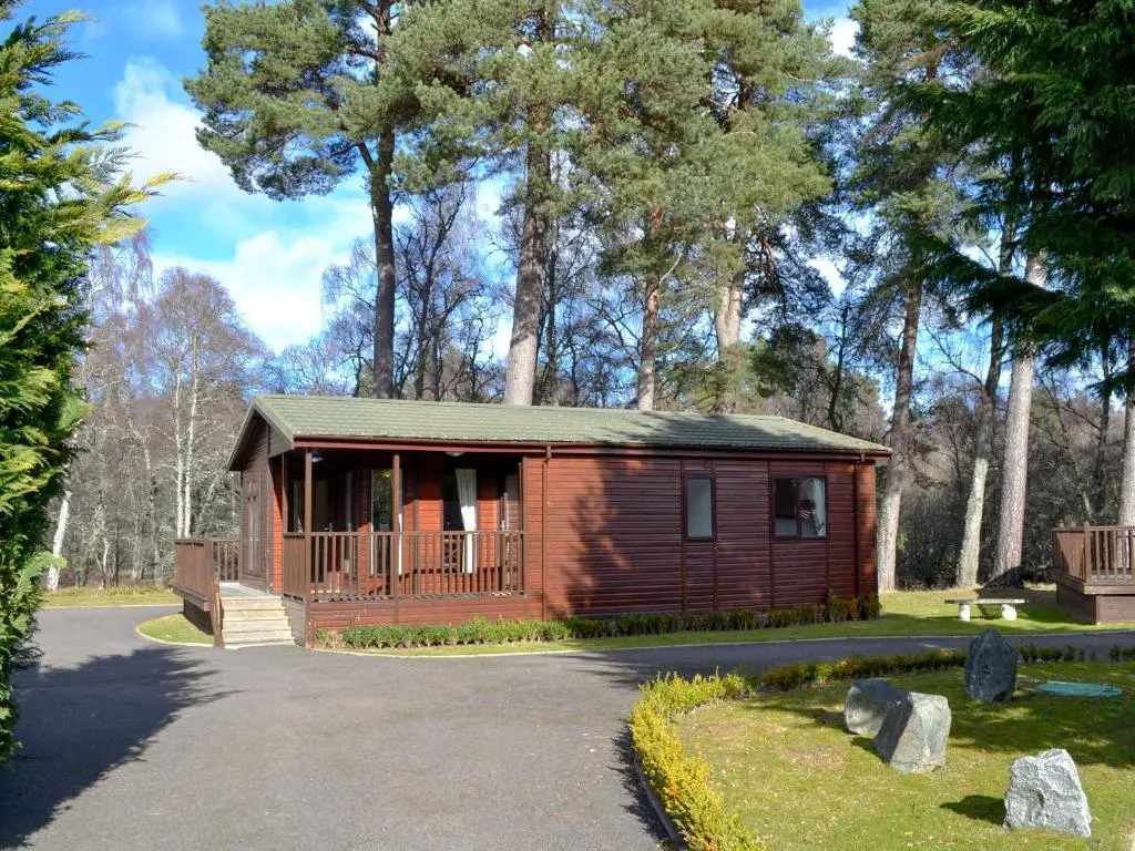 a small cabin in a park with trees at Lodge C- Uk33089 in Dinnet