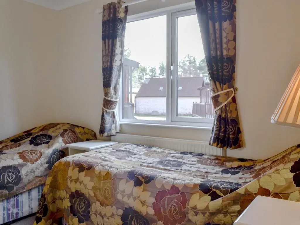 a bedroom with a bed and a window at Lodge C- Uk33089 in Dinnet