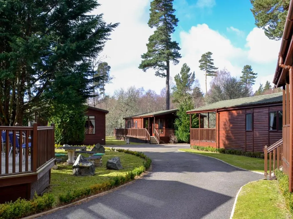 a path between two cabins in a resort at Lodge D- Uk33090 in Dinnet