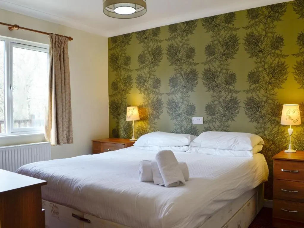 a bedroom with a bed with towels on it at Lodge A- Uk33088 in Dinnet