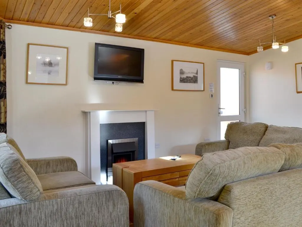 a living room with two couches and a fireplace at Lodge E- Uk33091 in Dinnet