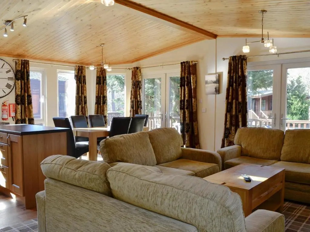 a living room with a couch and a table and chairs at Lodge E- Uk33091 in Dinnet