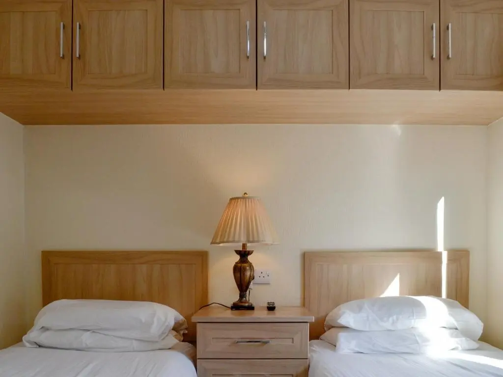 two beds in a room with wooden cabinets at Lodge E- Uk33091 in Dinnet
