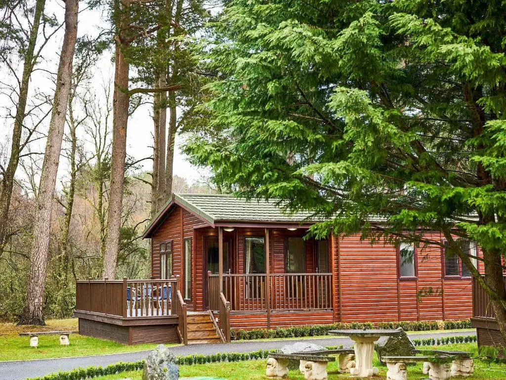 a small cabin in the woods with a deck at Lodge G- Uk33093 in Dinnet