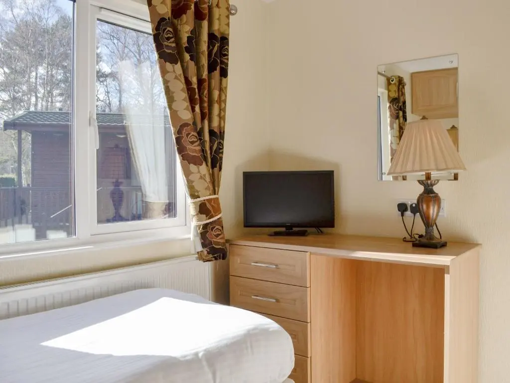 a bedroom with a bed and a tv and a window at Lodge G- Uk33093 in Dinnet