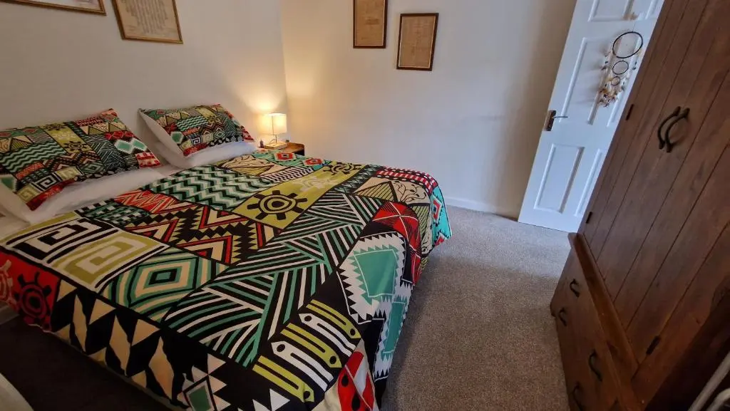 a bedroom with a bed with a colorful comforter at Meadows 2 in Auldearn
