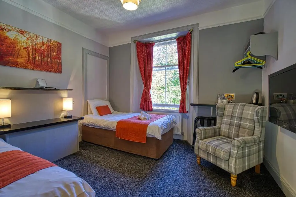 a bedroom with a bed and a chair and a window at Woodlands Bed and Breakfast in Dornoch