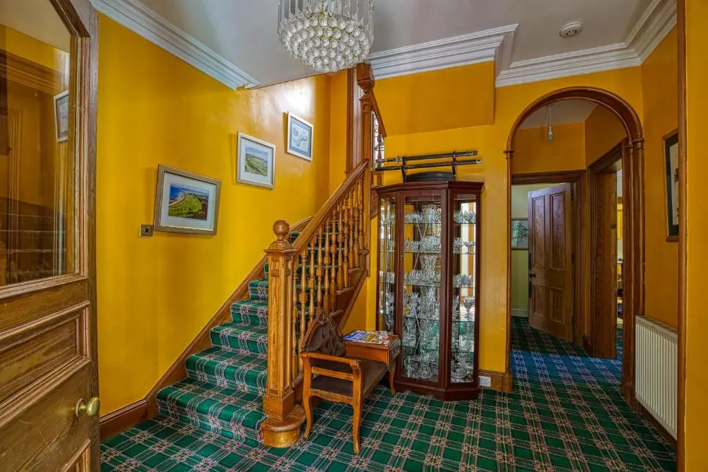 a hallway with a staircase and yellow walls at Woodlands Bed and Breakfast in Dornoch