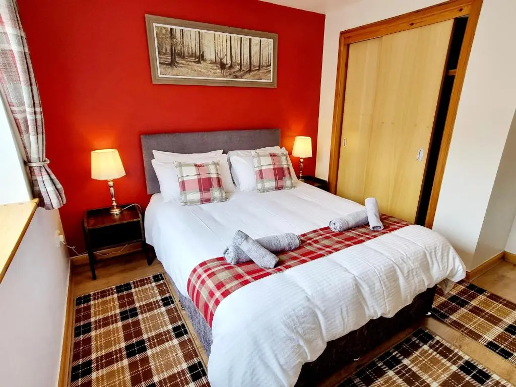 a bedroom with a large bed with red walls at Hill View 2 bedroom free parking in Inverness