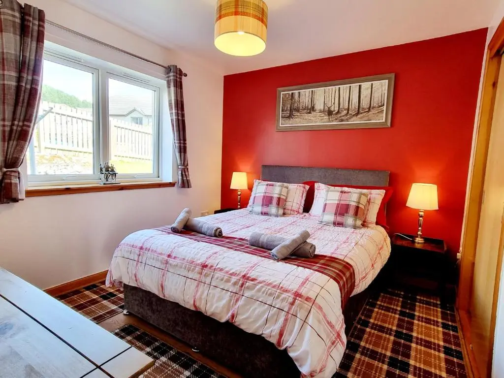 a red bedroom with a bed and two windows at Hill View 2 bedroom free parking in Inverness