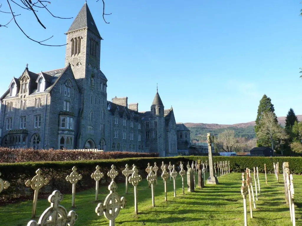 an old building with a cemetery in front of it at The Ness Apartment Highland Club Scotland in Fort Augustus