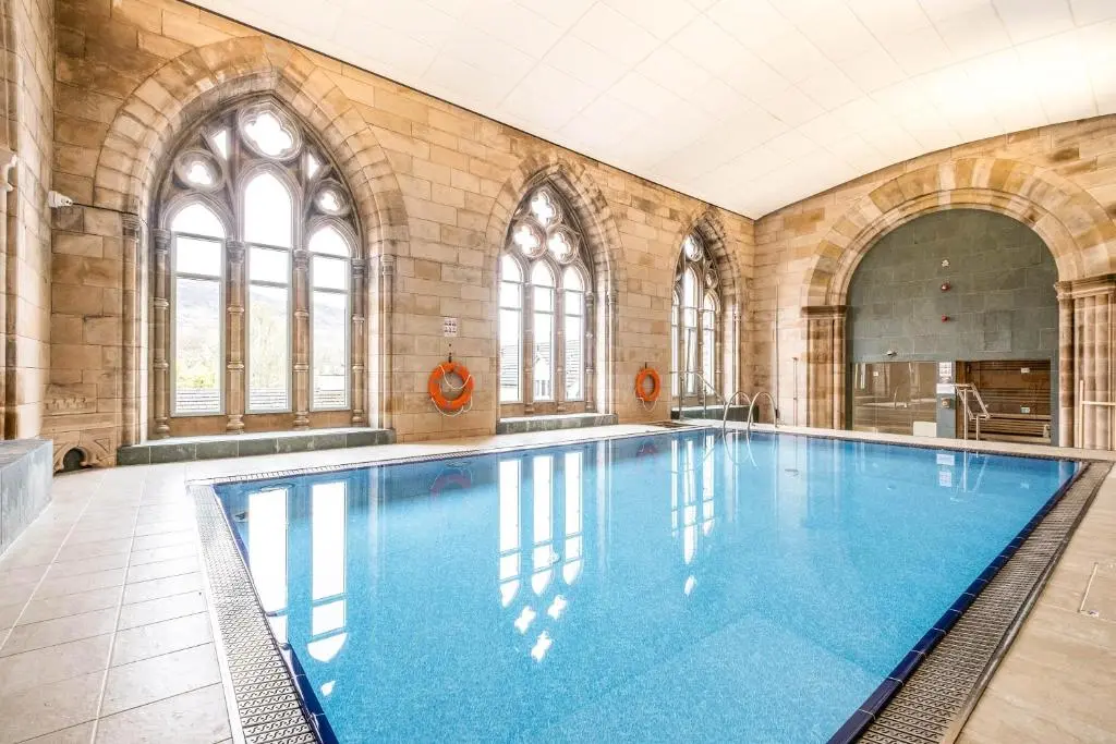 a large swimming pool in a building with windows at The Ness Apartment Highland Club Scotland in Fort Augustus