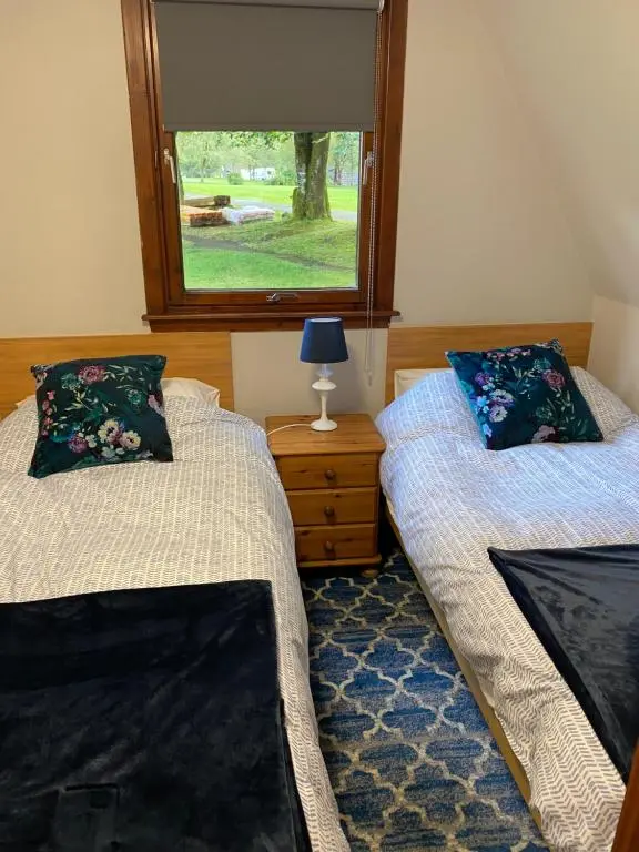 a bedroom with two beds and a window at Hayfield lodge in Spean Bridge