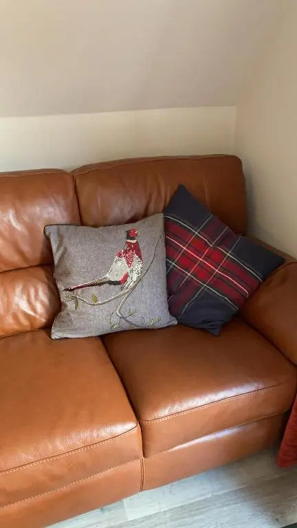 a brown leather couch with two pillows on it at Hayfield lodge in Spean Bridge