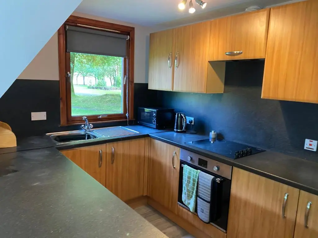 a kitchen with wooden cabinets and a sink and a window at Hayfield lodge in Spean Bridge