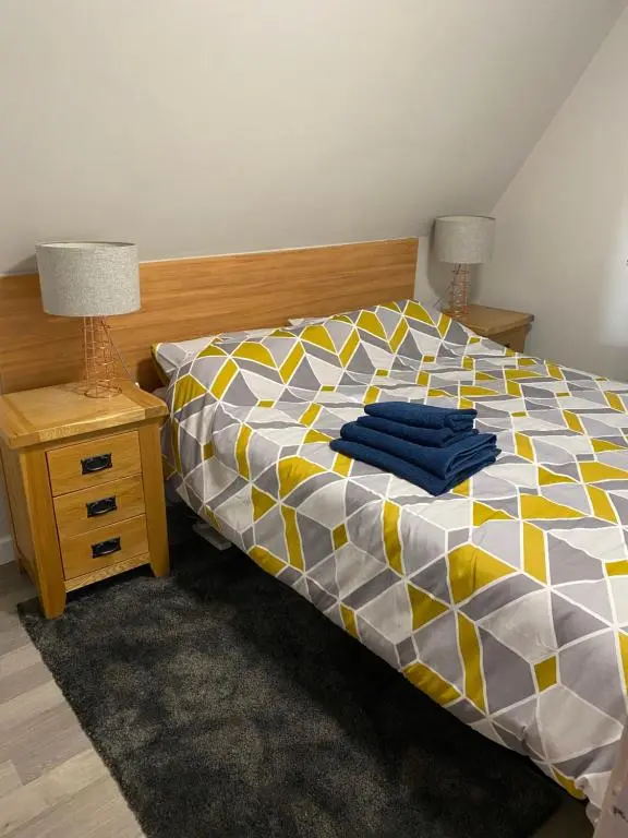 a bedroom with a bed and a night stand with two lamps at Hayfield lodge in Spean Bridge