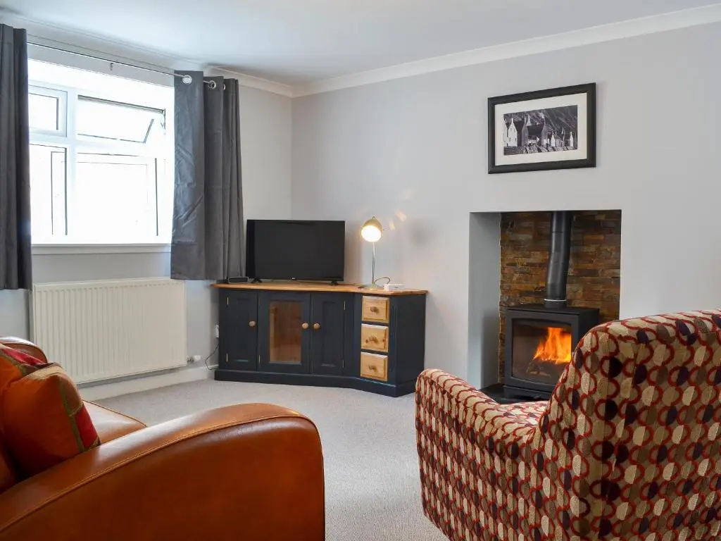 a living room with a fireplace and a television at Three Creeks Cottage in Portknockie