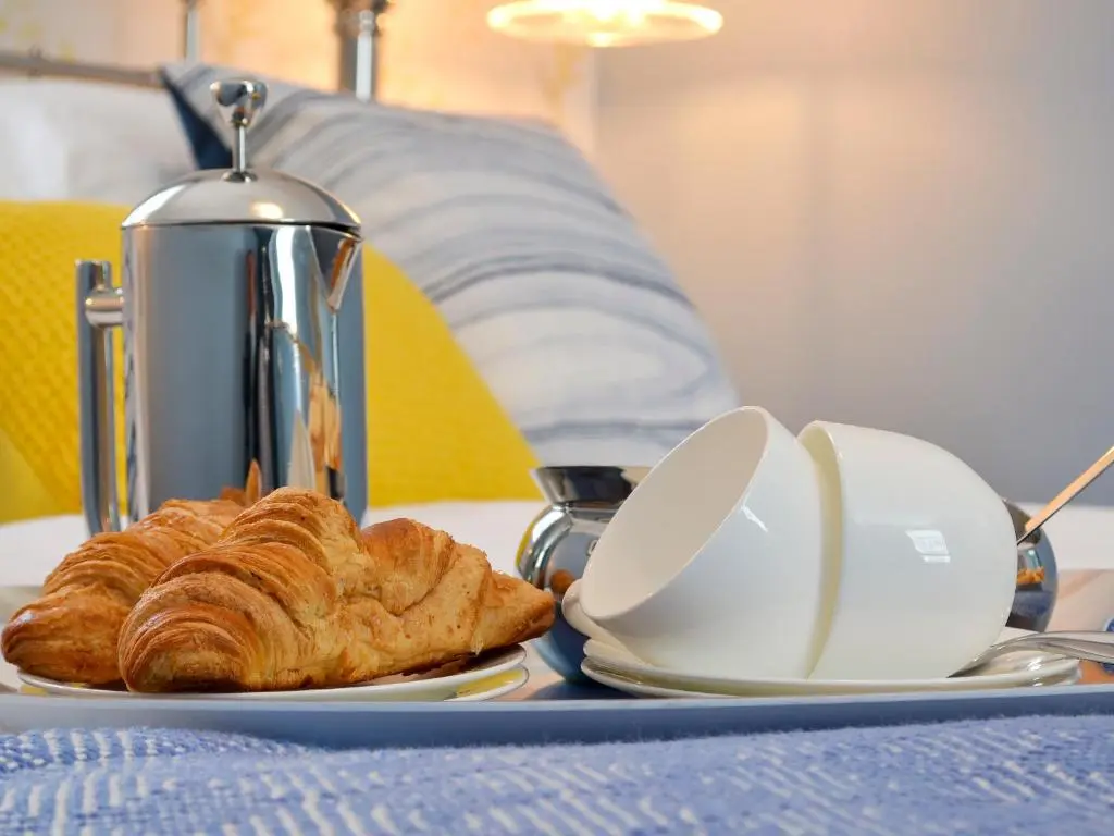 a table with a plate of croissants and a kettle at Three Creeks Cottage in Portknockie