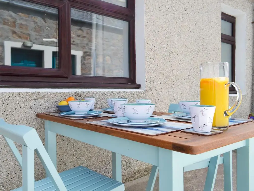 a table with a pitcher of orange juice on it at Three Creeks Cottage in Portknockie