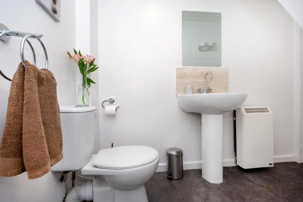 a white bathroom with a toilet and a sink at Finest Retreats - Ellie-Jo Cottage in Gardenstown