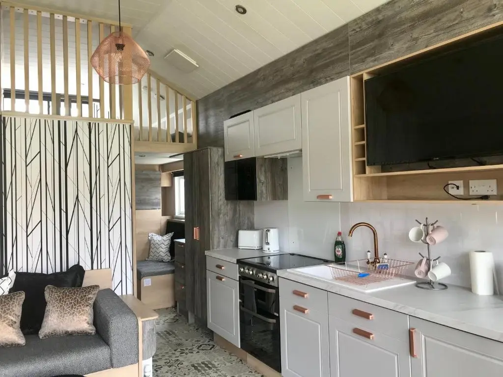 a kitchen with white cabinets and a couch in a room at 2 Bed Lodge - Sleeps 4 - Parking - Wifi in Inverness