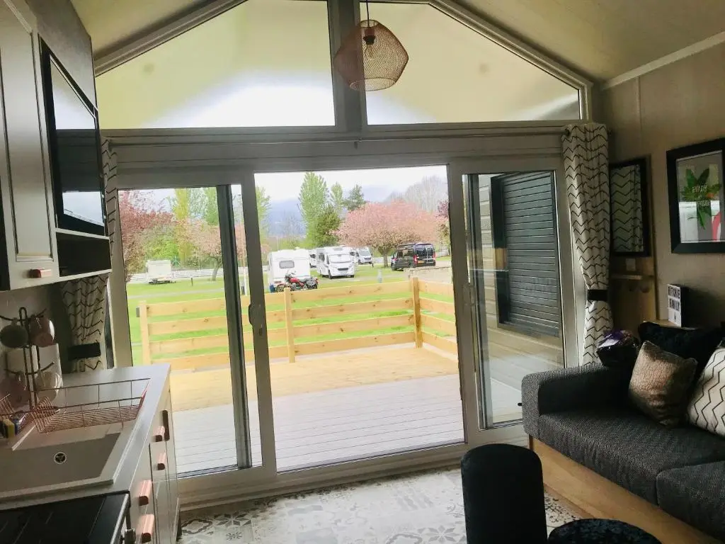 a living room with a sliding glass door with a view of a yard at Self-Catering Lodge with Hot Tub in Inverness