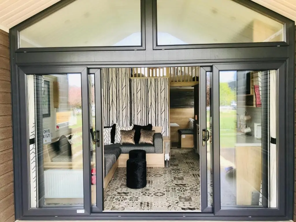 a living room with sliding glass doors and a couch at Self-Catering Lodge with Hot Tub in Inverness