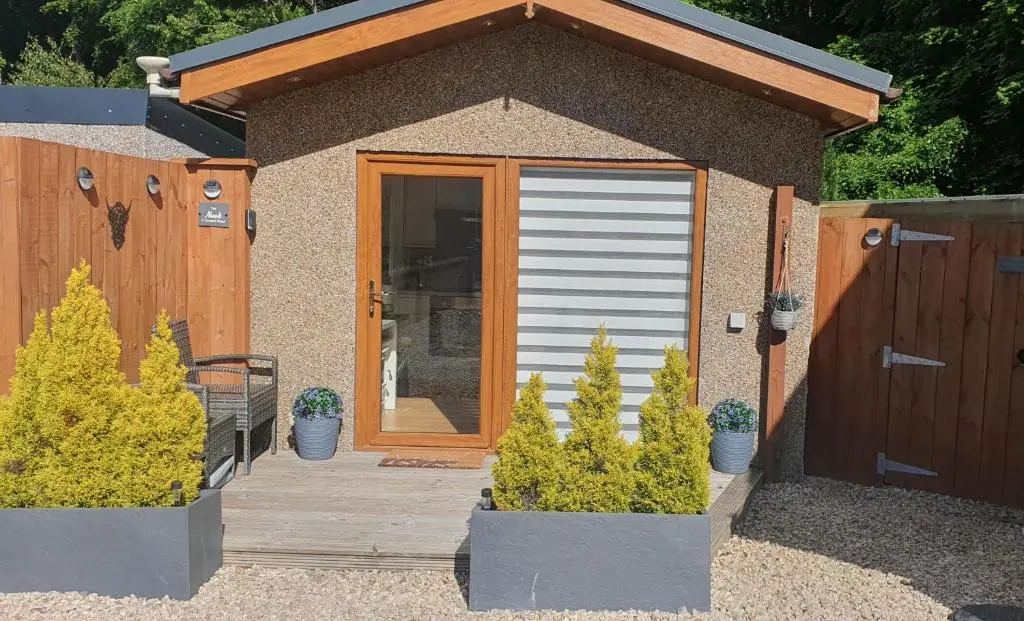 a shed with a wooden door and two potted plants at The Nook in Inverness