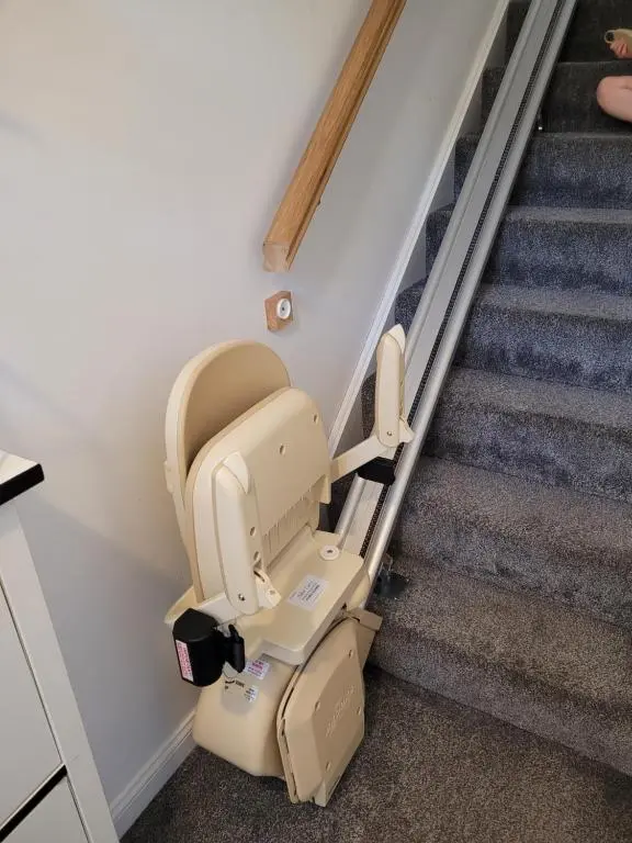 a beige infinity stair lift in a room with stairs at Kellys in Inverness