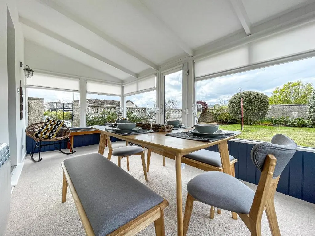 a dining room with a table and chairs and windows at Iseabail's House in Balintore
