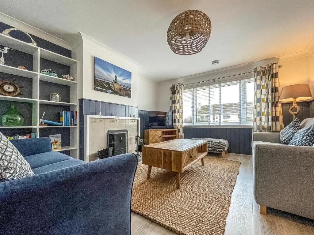 a living room with a blue couch and a table at Iseabail's House in Balintore