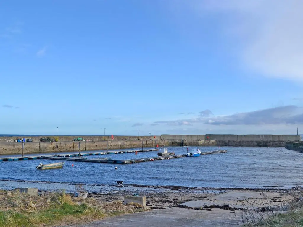 a river with two boats in the water at Iseabail's House in Balintore