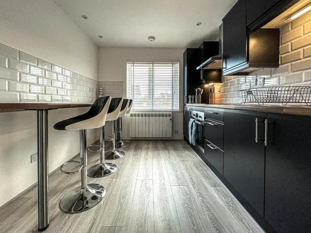 a kitchen with black cabinets and bar stools at Iseabail's House in Balintore