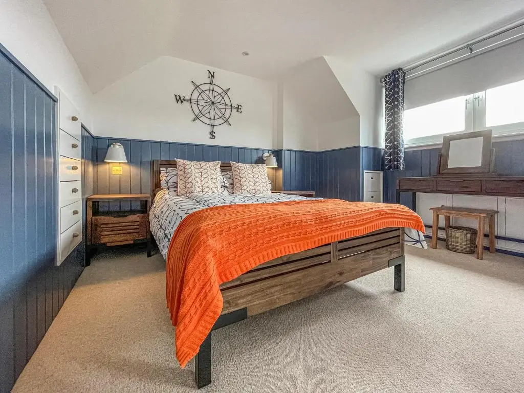 a bedroom with a large bed with an orange blanket at Iseabail's House in Balintore