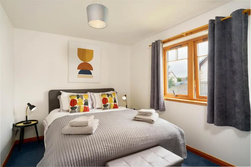 a bedroom with a bed with towels on it at The Nook Holiday Cottage in Aviemore