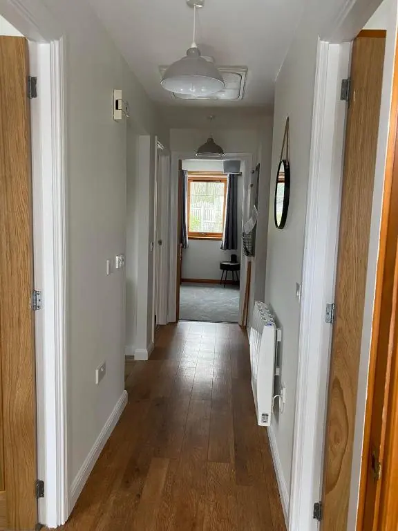 a hallway of a home with white walls and wooden floors at The Nook Holiday Cottage in Aviemore