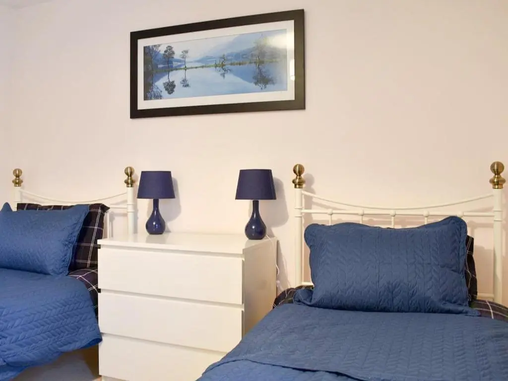a bedroom with two beds and a dresser at Lovely 2 bedroom apt in Ballater on the River Dee in Ballater