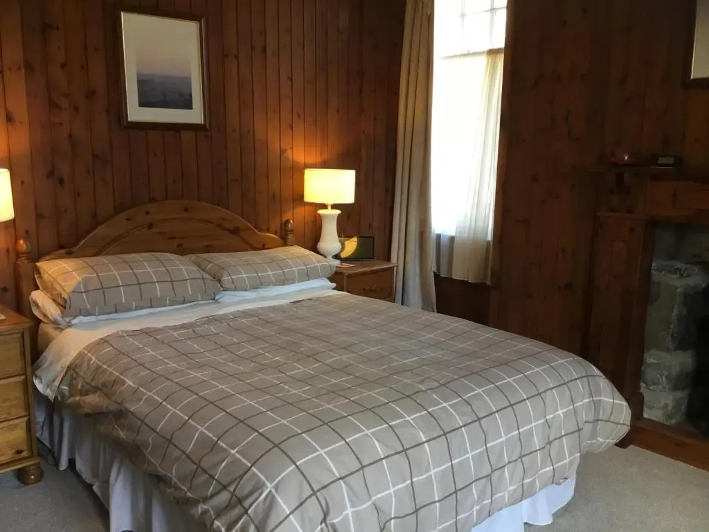 a bedroom with a bed and two lamps and a window at Westward Bed and Breakfast in Cannich