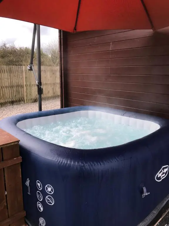 a hot tub with an umbrella in a yard at Lovely 1-Bed House in Fochabers Scotland in Fochabers