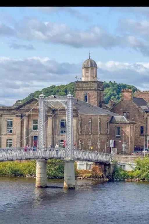 a bridge over a river in front of a building at Stunning spacious Apartment on River Ness in Inverness
