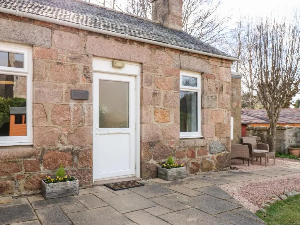 a stone house with a white door and windows at Gairnlea Cottage in Ballater