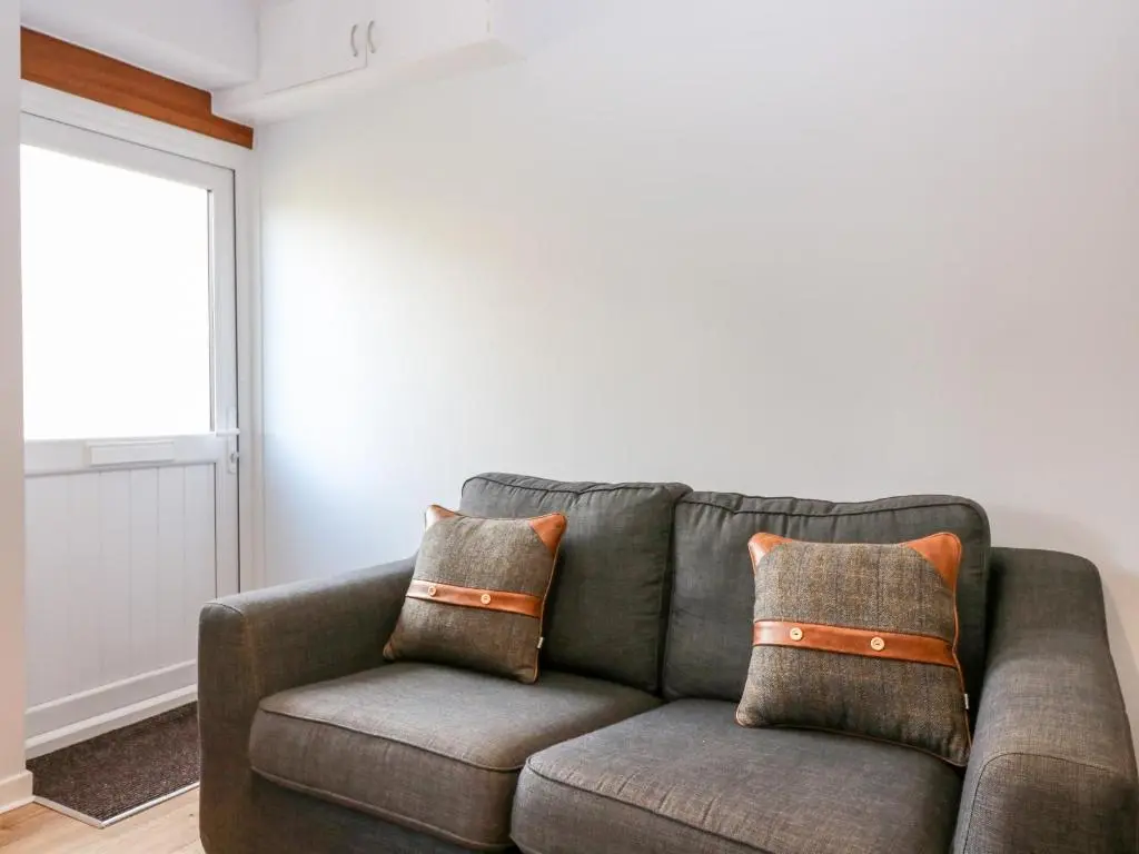 a gray couch with pillows in a living room at Gairnlea Cottage in Ballater