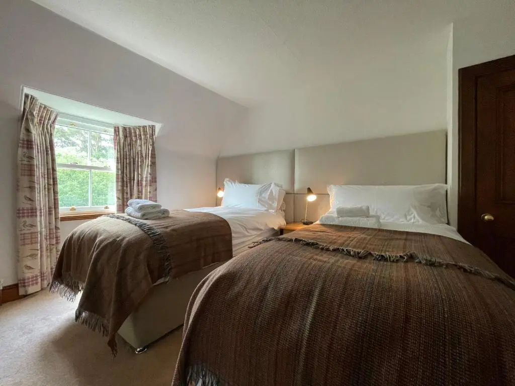 a bedroom with two beds and a window at Balloan Cottage in Dornoch