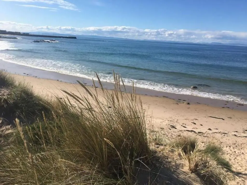 a sandy beach with the ocean and some grass at Lower Bruntlands in Fochabers