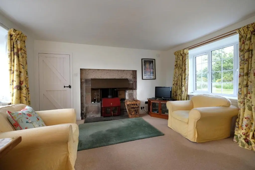 a living room with two chairs and a fireplace at Lower Bruntlands in Fochabers