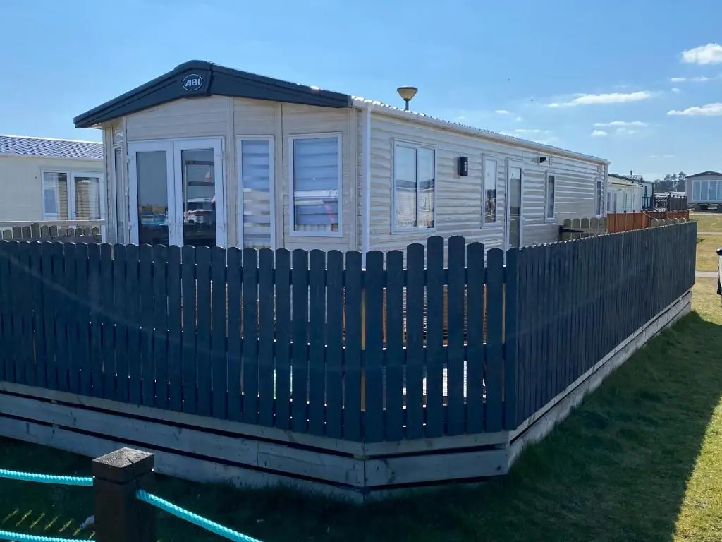 a house with a fence in front of it at Beachfront Lodge, Lossiemouth Bay in Lossiemouth