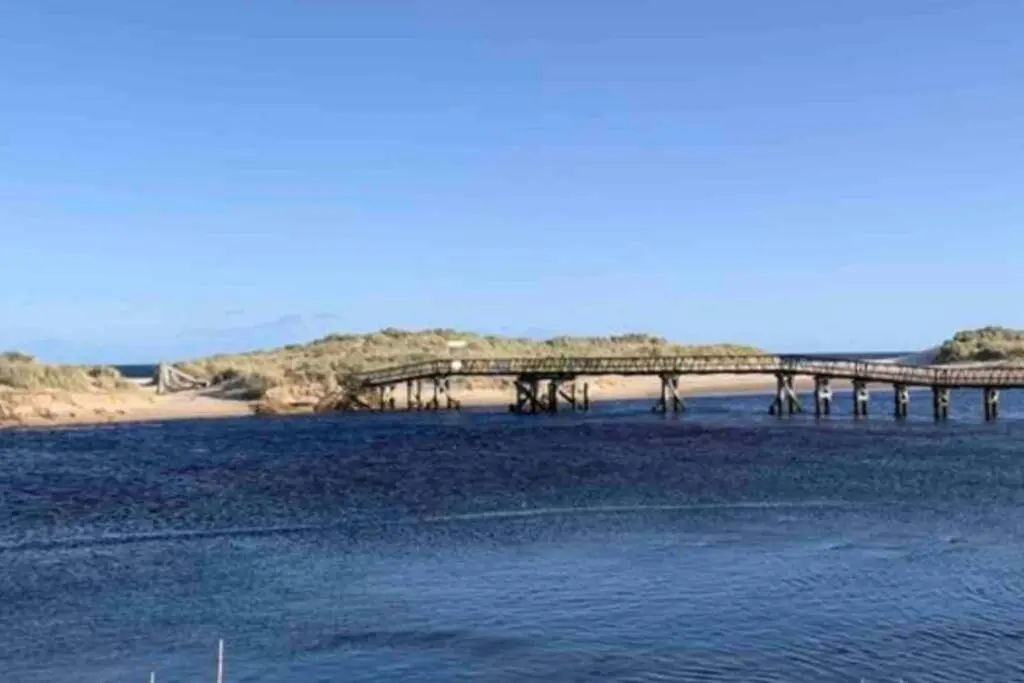 a bridge over a body of water next to a beach at Beachfront Lodge, Lossiemouth Bay in Lossiemouth
